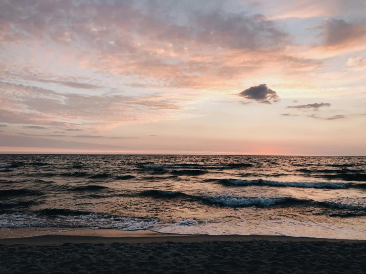 a large body of water sitting on top of a sandy beach, pexels contest winner, pink sunset, black sea, overcast skies, instagram post