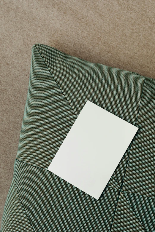 a piece of paper sitting on top of a pillow, by Harvey Quaytman, olive green, ui card, detaling, aerial