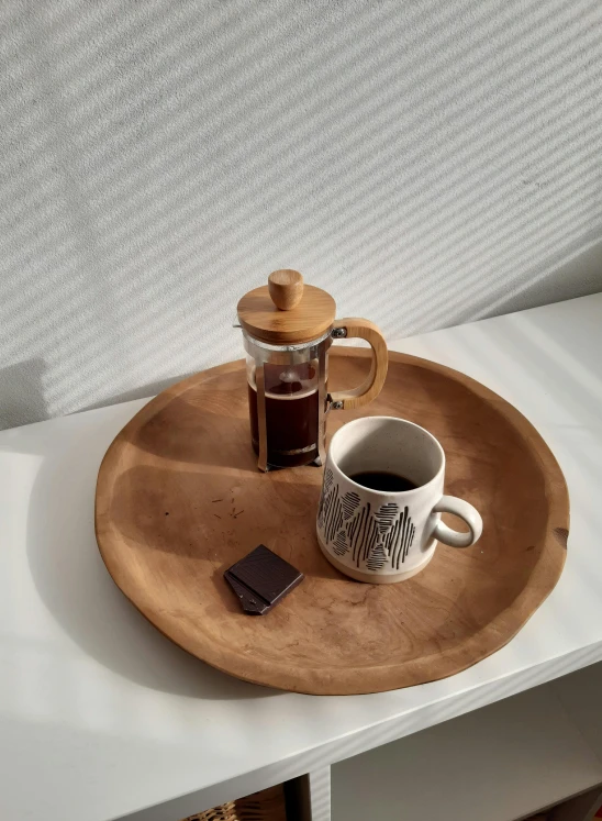 a cup of coffee sitting on top of a wooden tray, inspired by Ceferí Olivé, maple syrup, chocolate. rugged, curated collection, jakarta