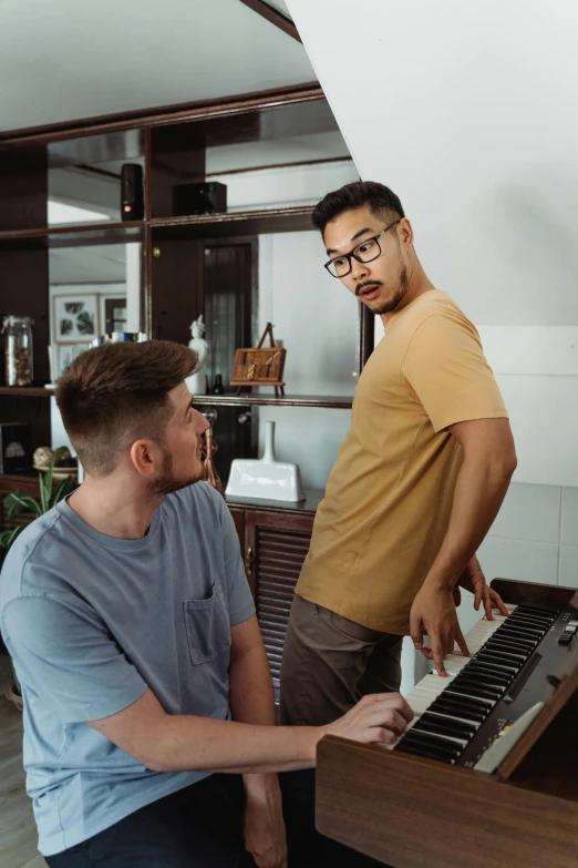 a couple of men standing next to each other near a piano, trending on reddit, half asian, calmly conversing 8k, full frame image, teaching