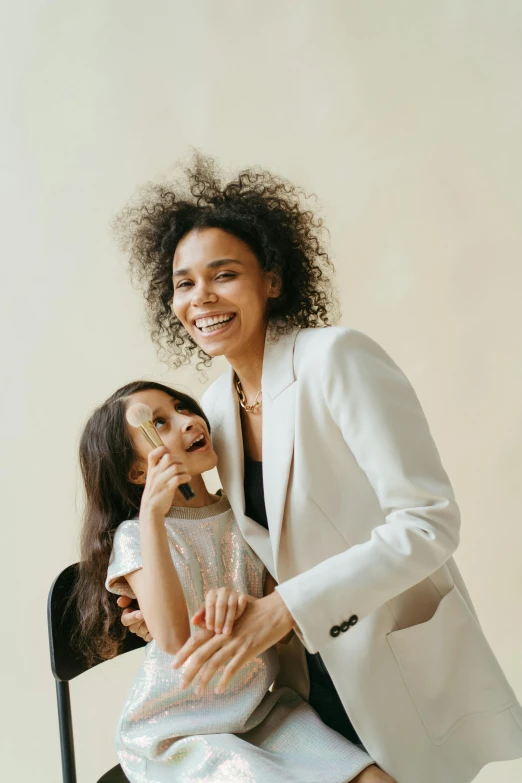 a woman sitting on top of a chair next to a little girl, wearing white suit, dark short curly hair smiling, gen z, - 6