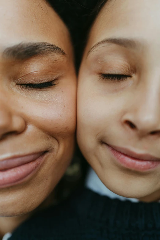 a couple of women standing next to each other, trending on pexels, closeup of face, smiling down from above, half - closed eyes, family friendly