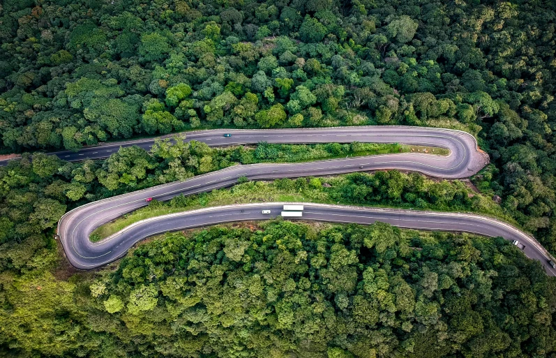 an aerial view of a winding road in the middle of a forest, conde nast traveler photo, avatar image, colombia, cars