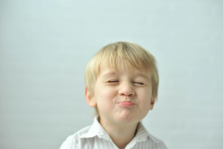 a young boy making a funny face with his eyes closed, pexels contest winner, kissing together cutely, small blond goatee, pointé pose;pursed lips, you g face