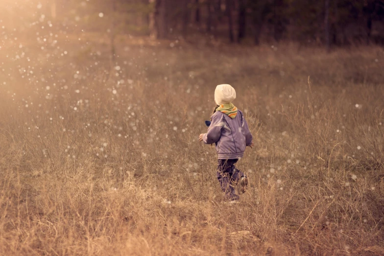 a little boy that is standing in the grass, by Lucia Peka, unsplash, conceptual art, winter season, fairy dust in the air, canvas, lachlan bailey