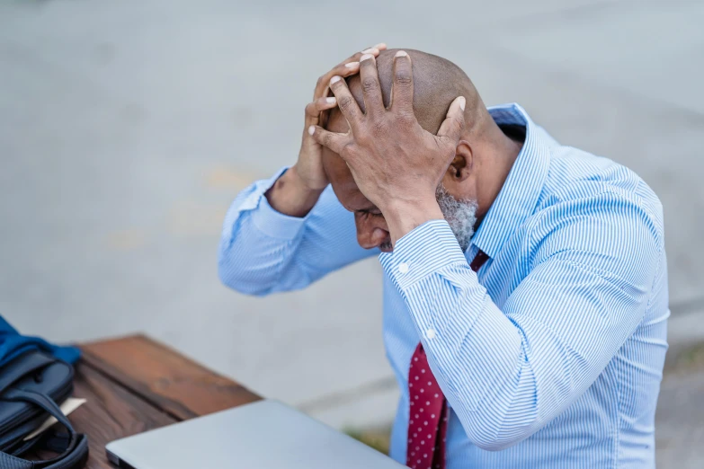 a man sitting at a table with his head in his hands, pexels, scratching head, bald man, slide show, sit on a bench