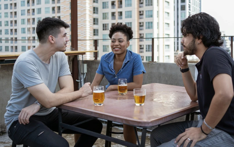 a group of people sitting around a wooden table, with a drink, profile image, city rooftop, avatar image