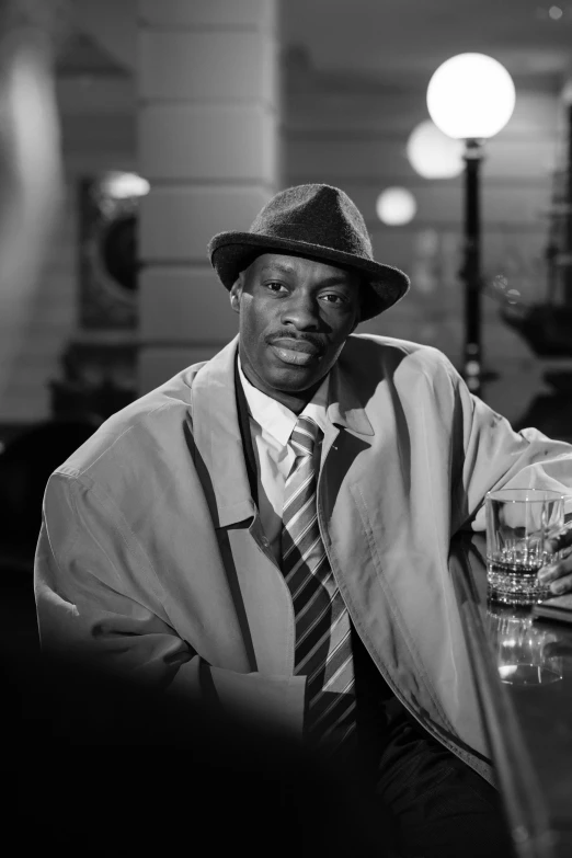 a black and white photo of a man sitting at a bar, harlem renaissance, pulp fiction style, jesse mccree, trench coat and suit, ( ( theatrical ) )