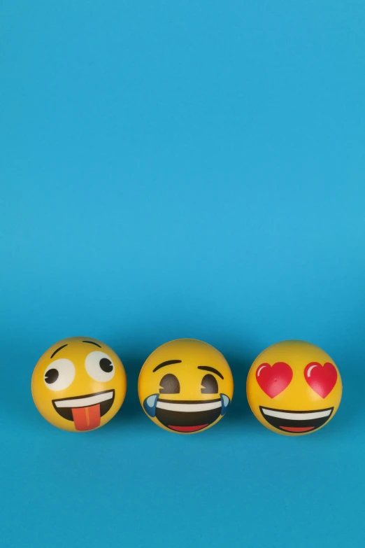 three smiley faces are lined up against a blue background, a picture, trending on pexels, inflatable, love, on a gray background, made of glazed