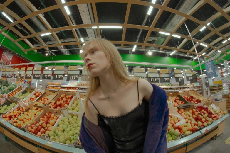 a woman standing in front of a fruit stand, an album cover, inspired by Elsa Bleda, reddit, hyperrealism, looks a blend of grimes, inside a supermarket, grim fashion model looking up, cinematic footage