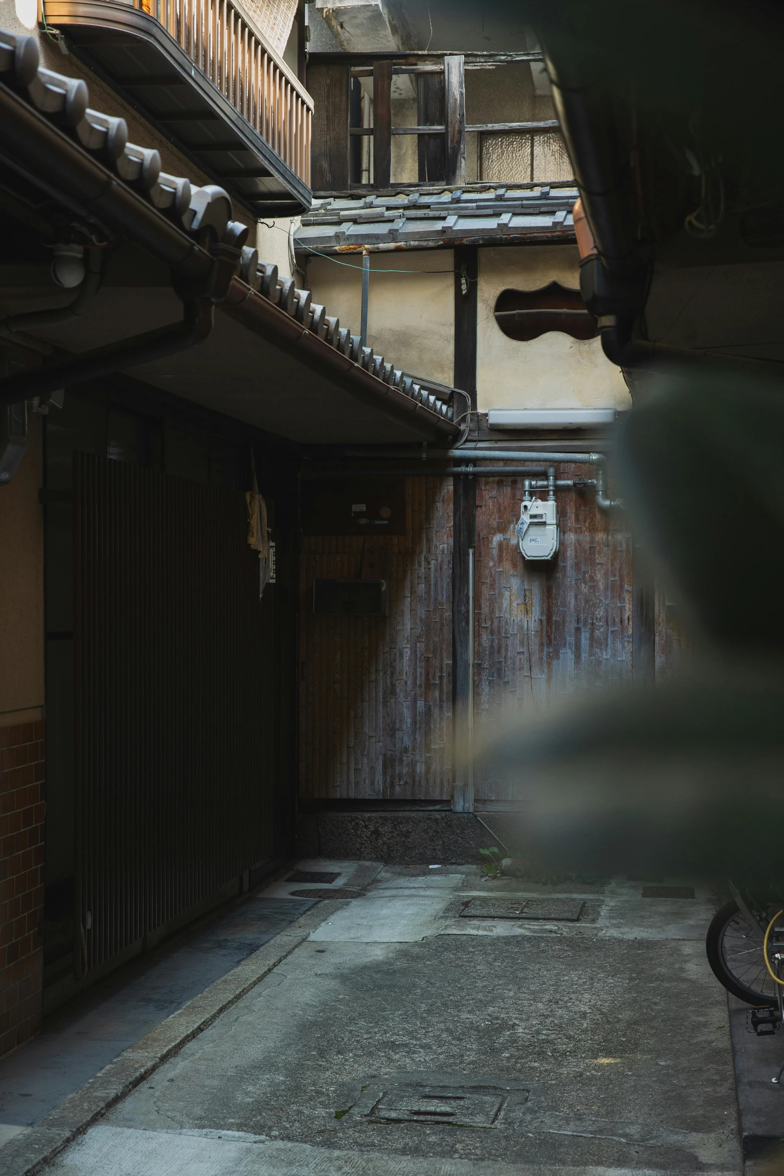 a bike is parked in a narrow alley, inspired by Maruyama Ōkyo, unsplash, shin hanga, mysterious exterior, wooden house, 4k], low quality photo