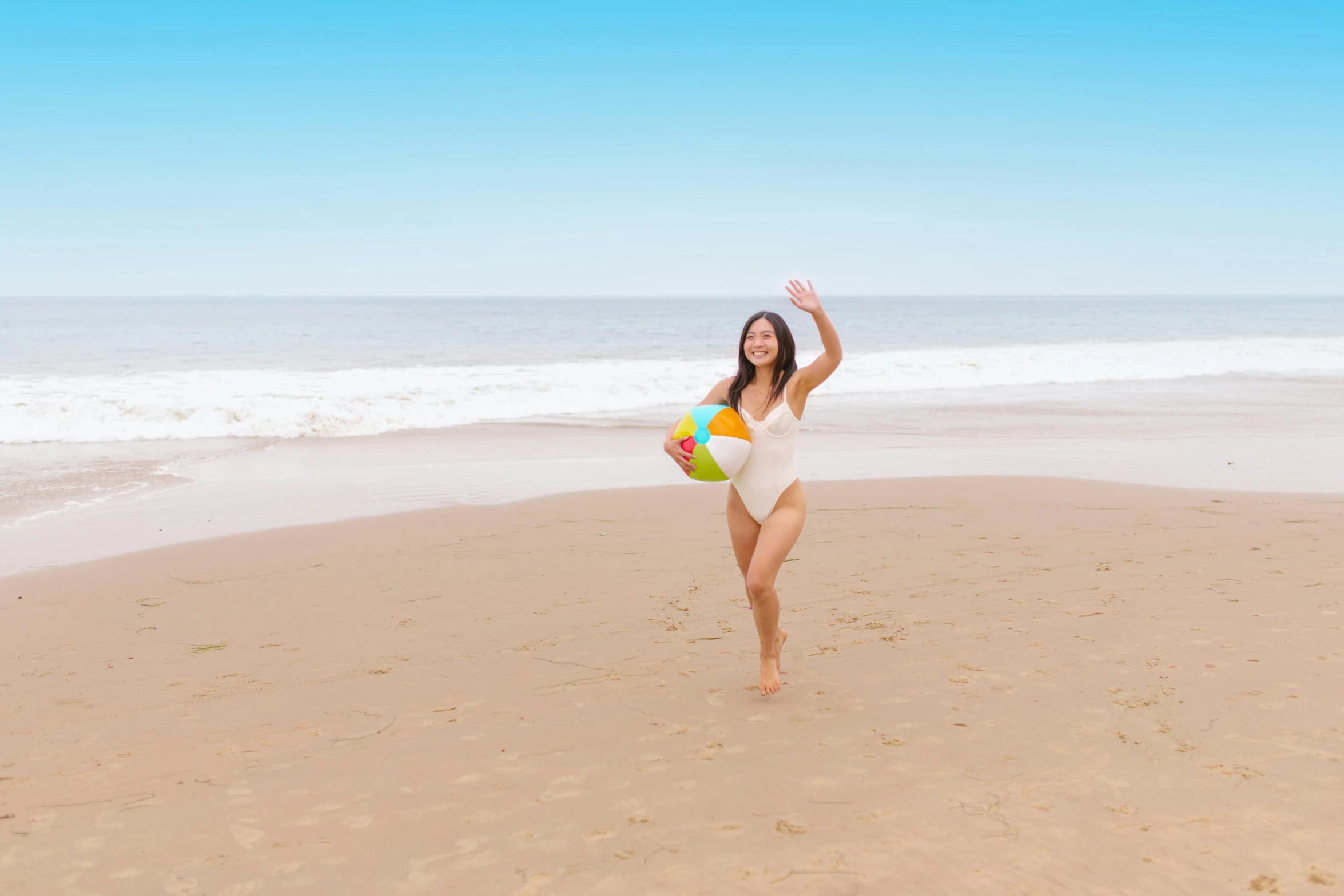 a woman is running on the beach with a ball, by Arabella Rankin, pexels contest winner, monokini, white, pregnancy, waving and smiling