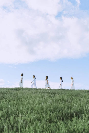 a group of people walking across a lush green field, inspired by Vanessa Beecroft, pexels contest winner, land art, wearing a white dress, ( ( theatrical ) ), girls, rinko kawauchi