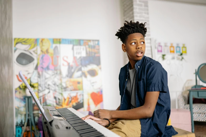 a young man sitting in front of a keyboard, trending on pexels, black arts movement, an instrument, avatar image