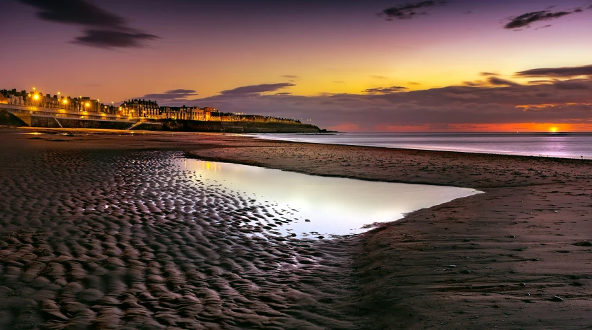 a large body of water sitting on top of a sandy beach, by David Donaldson, pexels contest winner, baroque, neon reflections in the puddles, medieval coastal village, during dawn, high-resolution photo