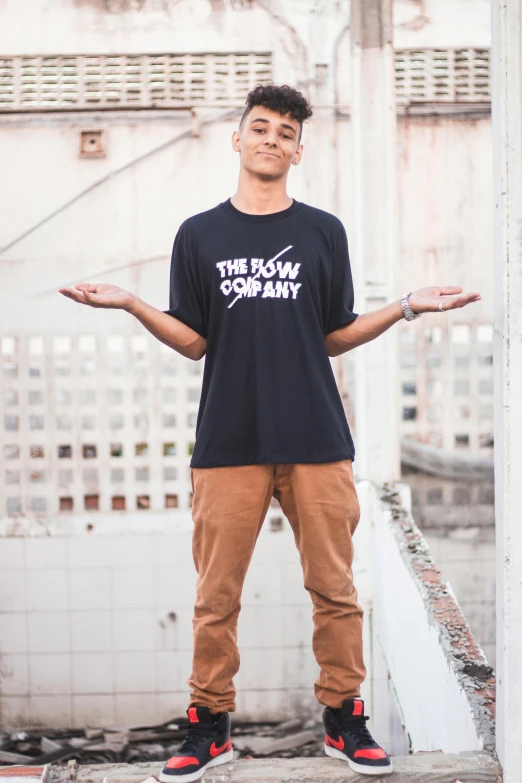 a young man wearing a black shirt and tan pants, by Brian Snøddy, featured on instagram, graffiti, standup comedian, bow and arrow, official product image, in white lettering