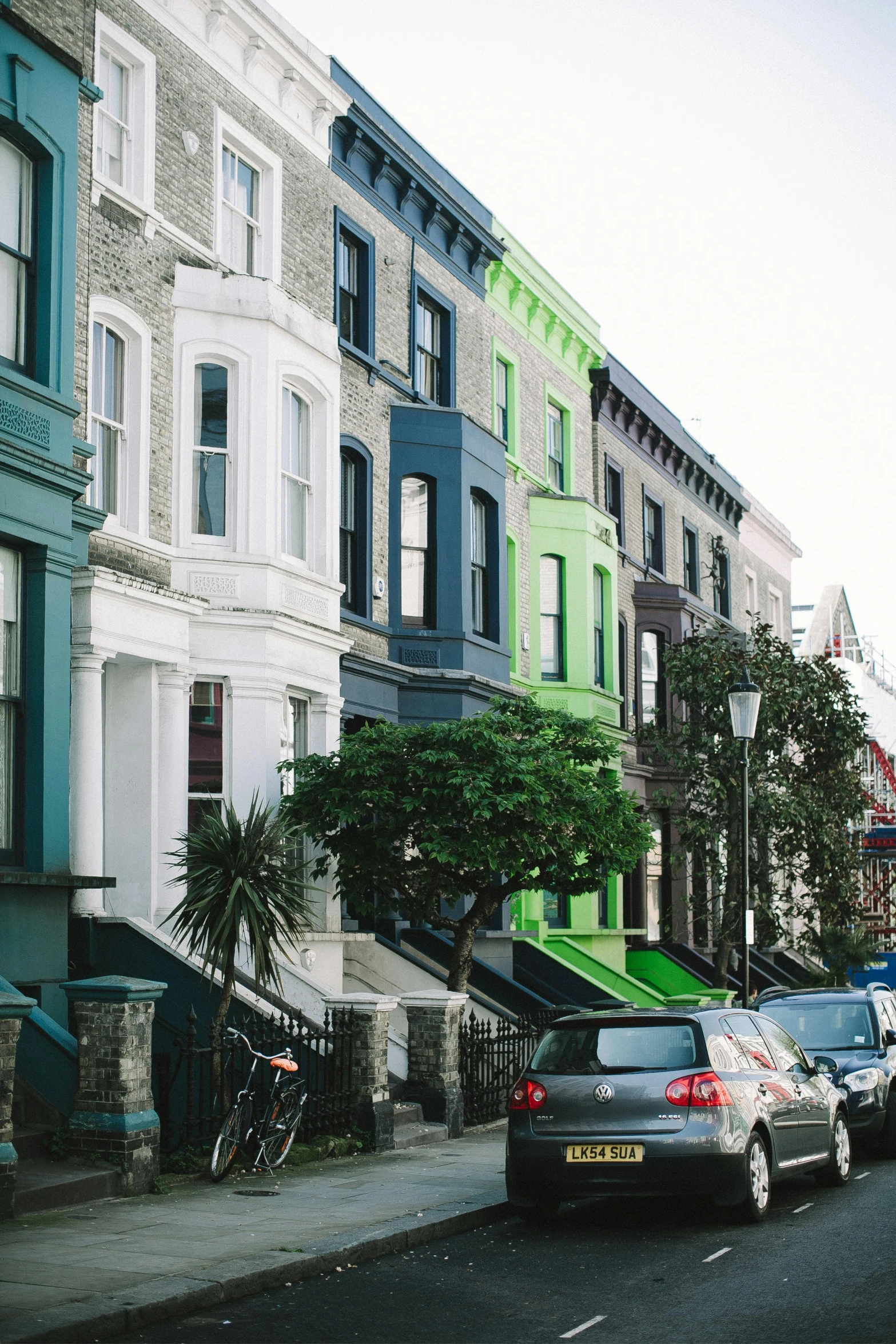 a street filled with lots of parked cars, by Washington Allston, trending on unsplash, neoclassicism, victorian house, exterior view, multi - coloured, terraced