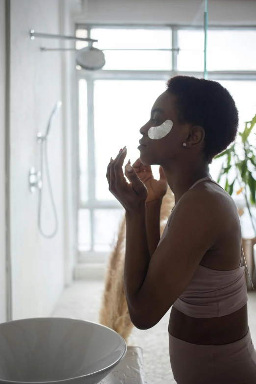 a woman is shaving her face in the bathroom, by Cosmo Alexander, black eye mask, dark complexion, onsens, sun set