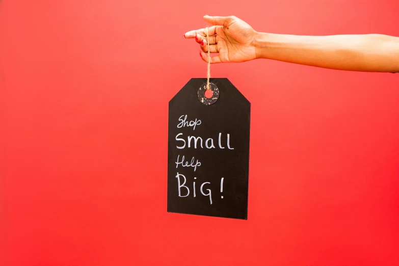 a person holding a tag with the words small things big written on it, by Julia Pishtar, high resolution print :1 red, chalkboard, ecommerce photograph, red and black colour scheme