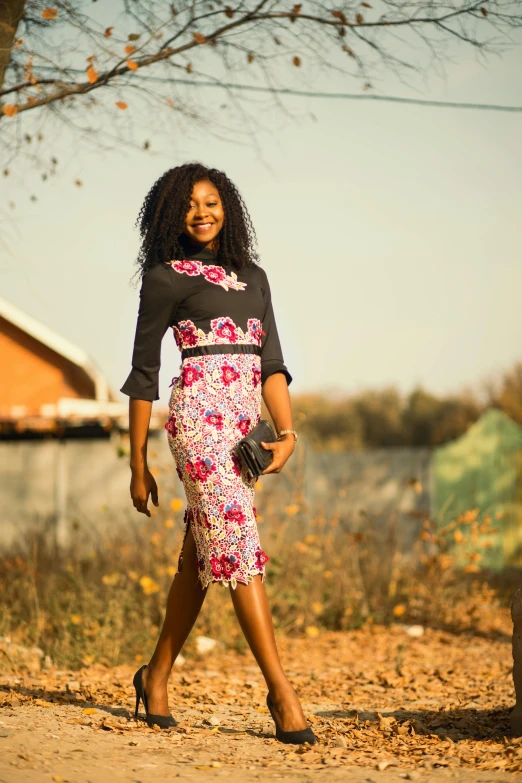 a woman walking down a dirt road next to a tree, a portrait, inspired by Chinwe Chukwuogo-Roy, pexels contest winner, floral clothes ”, business attire, black and pink dress, february)