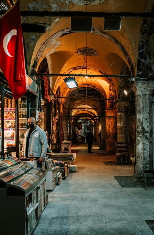 a man standing in front of a book store, a colorized photo, pexels contest winner, archways between stalagtites, istanbul, inspect in inventory image, beautiful low light