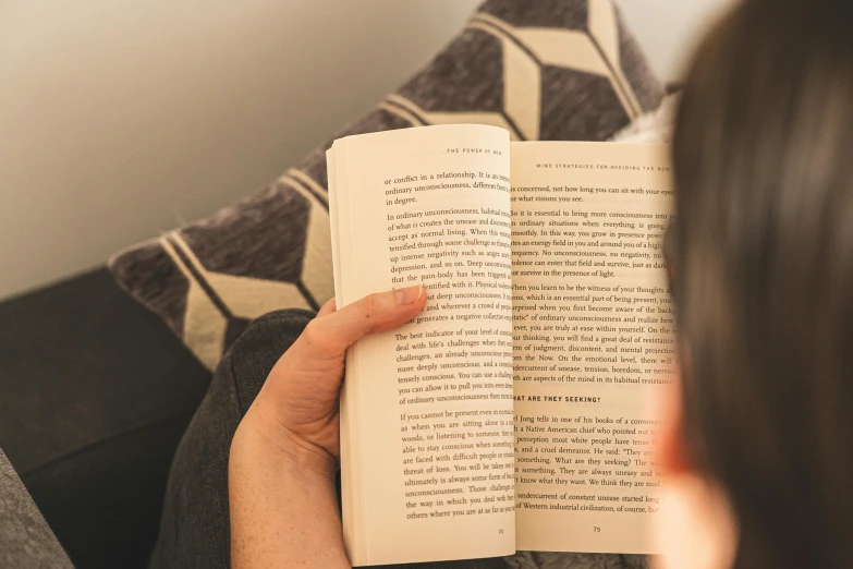 a person reading a book on a couch, by Carey Morris, pexels, someone sits in bed, over the shoulder shot, plain background, unreadable text