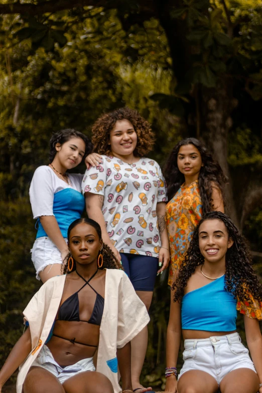 a group of women sitting next to each other, an album cover, by Lily Delissa Joseph, trending on pexels, dressed in a top and shorts, brazilian, headshot, ( ( brown skin ) )