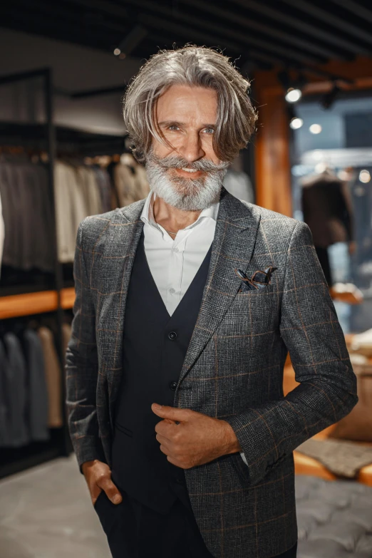 a man in a suit standing in a clothing store, grey trimmed beard, style of maciej kuciara, rich in texture ), creterion collection