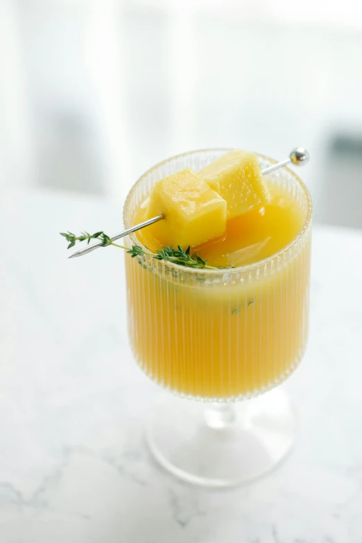 a glass filled with orange juice and garnished with a sprig of thyme, inspired by Évariste Vital Luminais, renaissance, pineapple, jen yoon, mango, dynamic angled shot