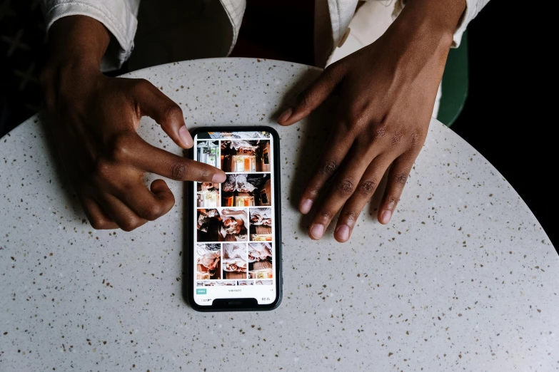 a person sitting at a table with a cell phone, a picture, trending on pexels, happening, ( ( dark skin ) ), with index finger, instagram digital, thumbnail