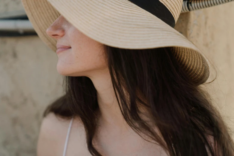 a close up of a person wearing a hat, in the sun