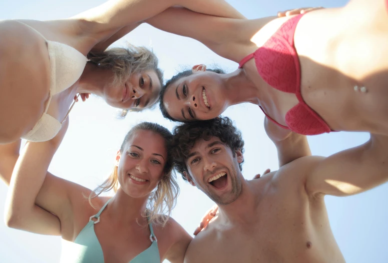 a group of people standing around each other, having fun in the sun, coerent face and body, bottom angle, smiling into the camera