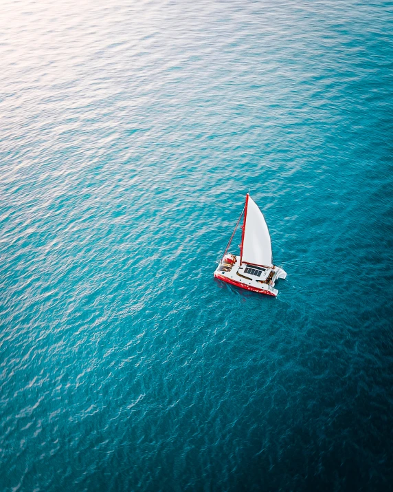 a sailboat floating in the middle of the ocean, pexels contest winner, red and teal color scheme, thumbnail, flatlay, manly