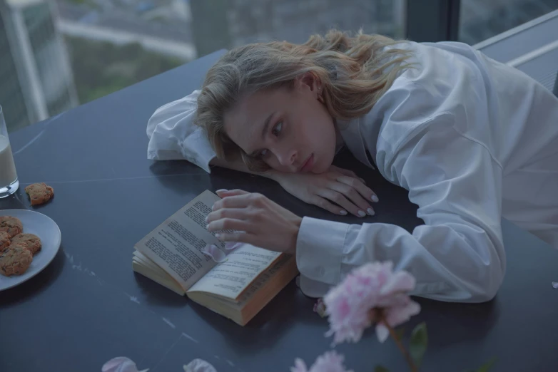 a woman laying on top of a table next to a book, inspired by Elsa Bleda, pexels contest winner, romanticism, imogen poots paladin, looking tired, sydney sweeney, flowers around