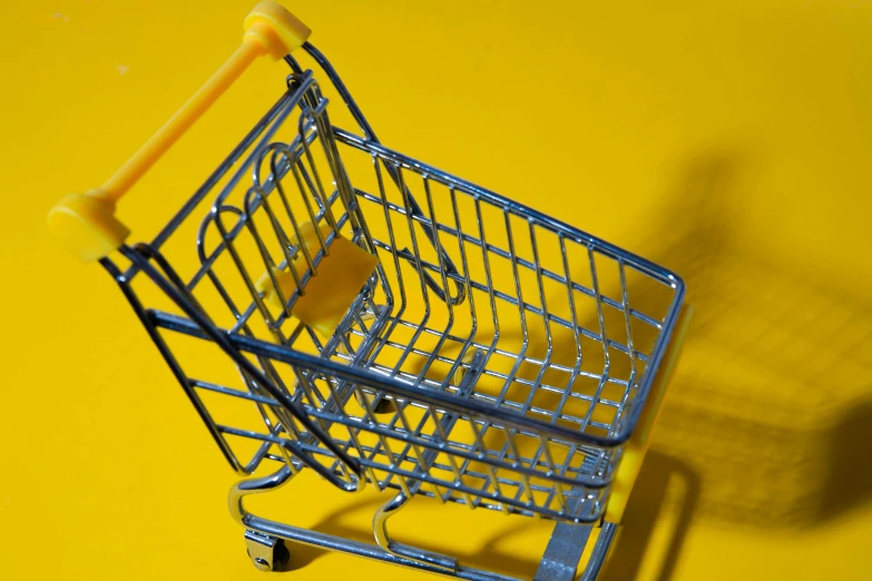 a miniature shopping cart on a yellow surface, pexels, hyperrealism, square, silver, item, cart