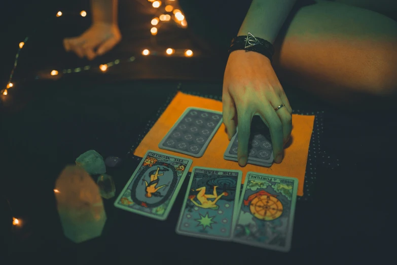 a close up of a person holding tarot cards, by Julia Pishtar, pexels contest winner, holographic runes, wizard doing a tarot reading, nighttime, game board