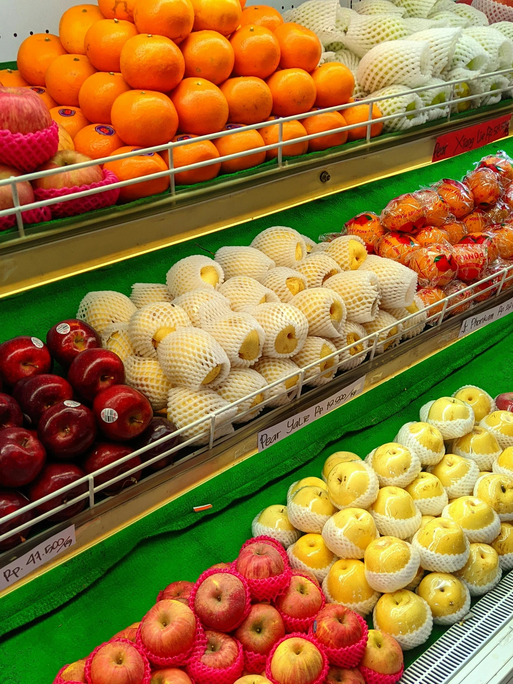 a display case filled with lots of fruits and vegetables, a close up shot, food, fruit, apple orange