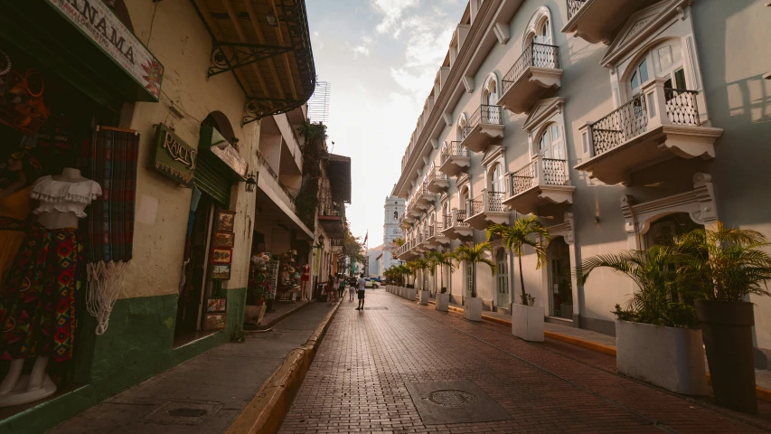 a couple of people walking down a street next to tall buildings, pexels contest winner, renaissance, tlaquepaque, early morning light, tropical coastal city, thumbnail