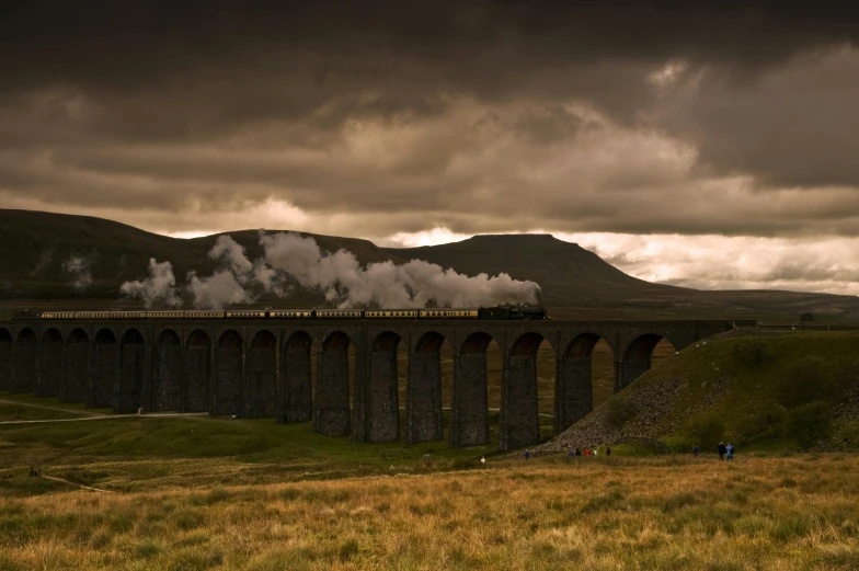 a train traveling over a bridge on a cloudy day, by Andrew Geddes, pexels contest winner, steam workshop maps, marsden, historically accurate, deep colours. ”