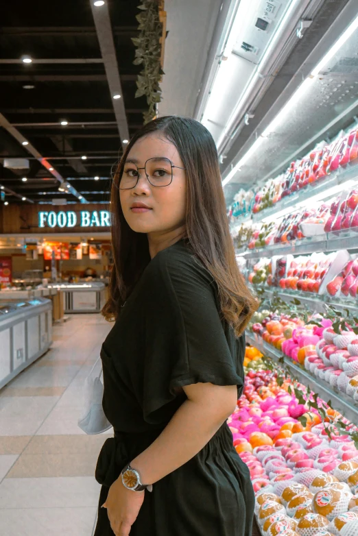 a woman standing in front of a display of donuts, inspired by Tan Ting-pho, pexels contest winner, hyperrealism, stood in a supermarket, girl wearing round glasses, headshot profile picture, mall background