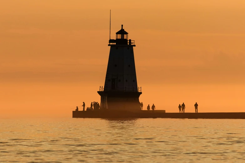 a light house sitting on top of a body of water, by Greg Rutkowski, unsplash contest winner, crowded silhouettes, michigan, 1 6 x 1 6, light orange mist