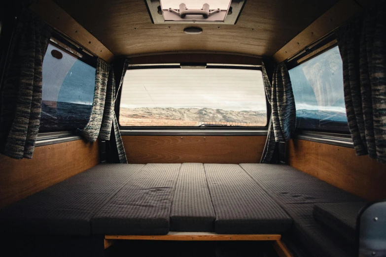 a bed sitting inside of a van next to a window, by Carey Morris, unsplash contest winner, fan favorite, bottom angle, open top, ben ridgway
