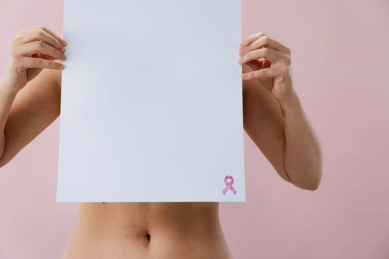 a woman holding a sheet of paper in front of her face, trending on pexels, antipodeans, pink body harness, belly button showing, ribbon, medical image