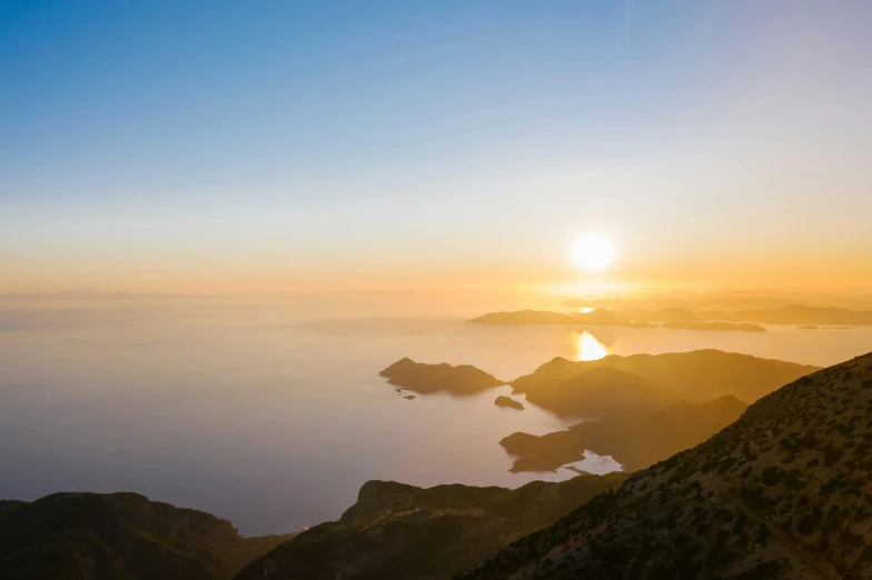 a person standing on top of a mountain at sunset, pexels contest winner, romanticism, croatian coastline, “ aerial view of a mountain, golden sun, at sunrise in springtime