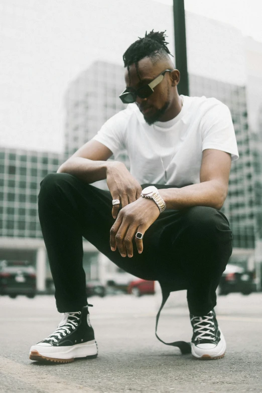a man sitting on a skateboard in a parking lot, an album cover, inspired by Theo Constanté, trending on pexels, doing an elegant pose, kendrick lamar, profile image, wearing pants and a t-shirt