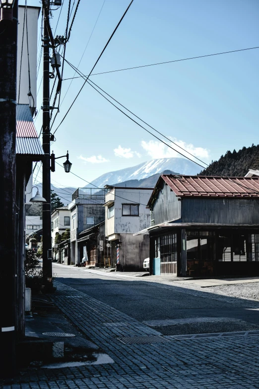 a red fire hydrant sitting on the side of a road, a picture, by Yasushi Sugiyama, trending on unsplash, mingei, old village in the distance, mount fuji, wires hanging above street, driving through a 1 9 5 0 s town