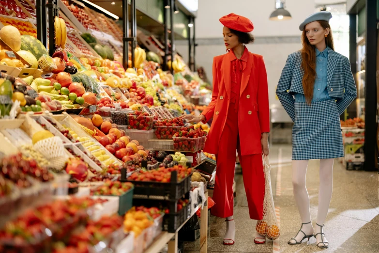 a couple of women standing next to each other in front of a fruit stand, a digital rendering, by Julia Pishtar, trending on pexels, red suit, inside a supermarket, chanel, red hat