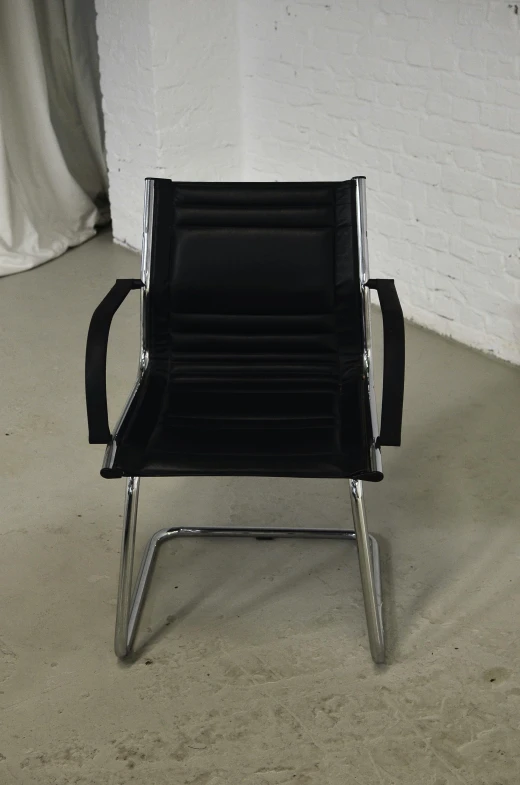 a black chair sitting in front of a white wall, style of hr geiger, 12, fine, front