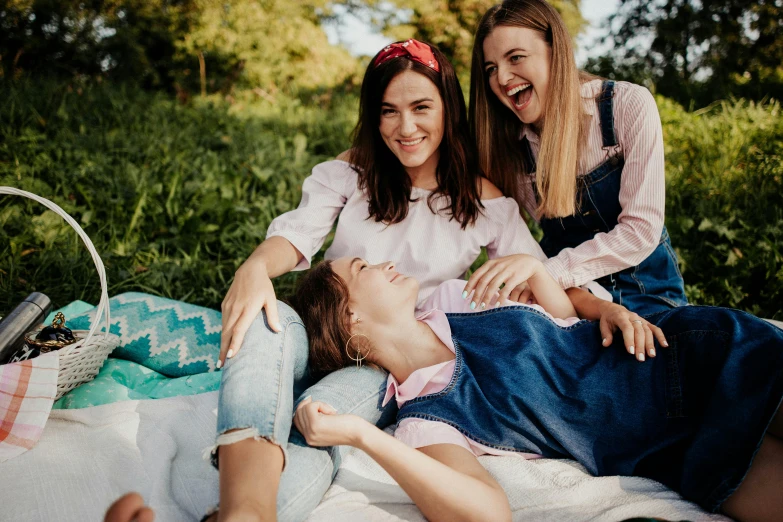 a couple of women laying on top of a blanket, a picture, trending on pexels, three women, people on a picnic, 15081959 21121991 01012000 4k, laughing menacingly