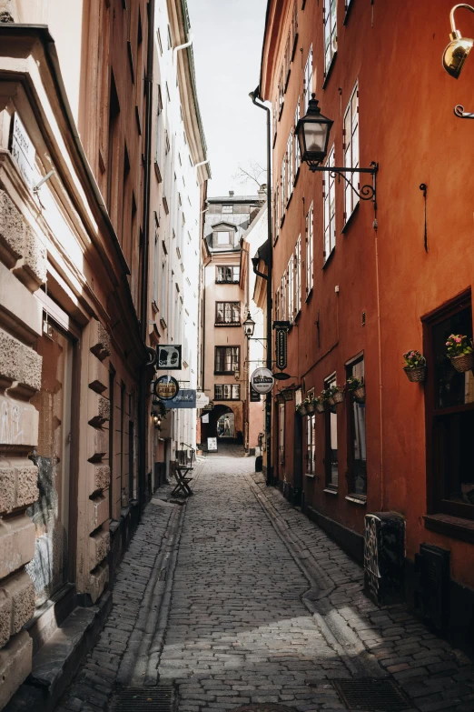 a narrow cobblestone street in a european city, by Tom Wänerstrand, unsplash contest winner, stockholm, muted colors. ue 5, orange, small buildings